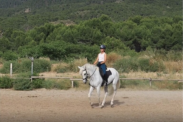 Chica galopando a caballo en pista