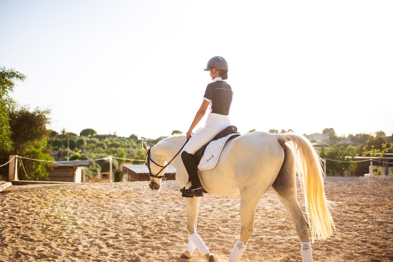 Chica montando a caballo de espaldas